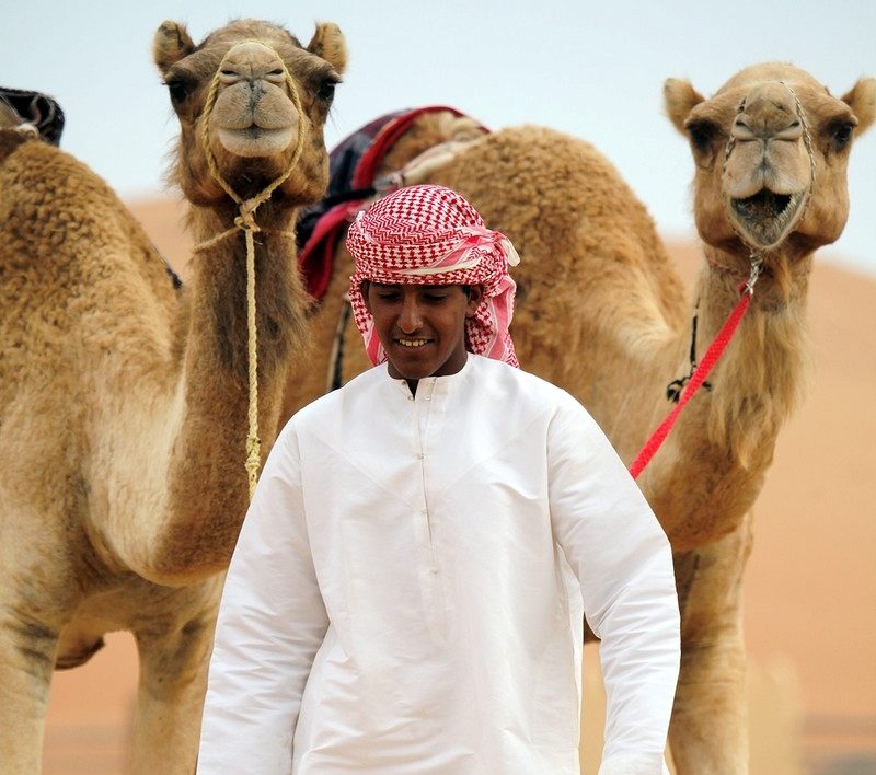 Rondreis-Oman-man-wandelt-met-zijn-dromedarissen