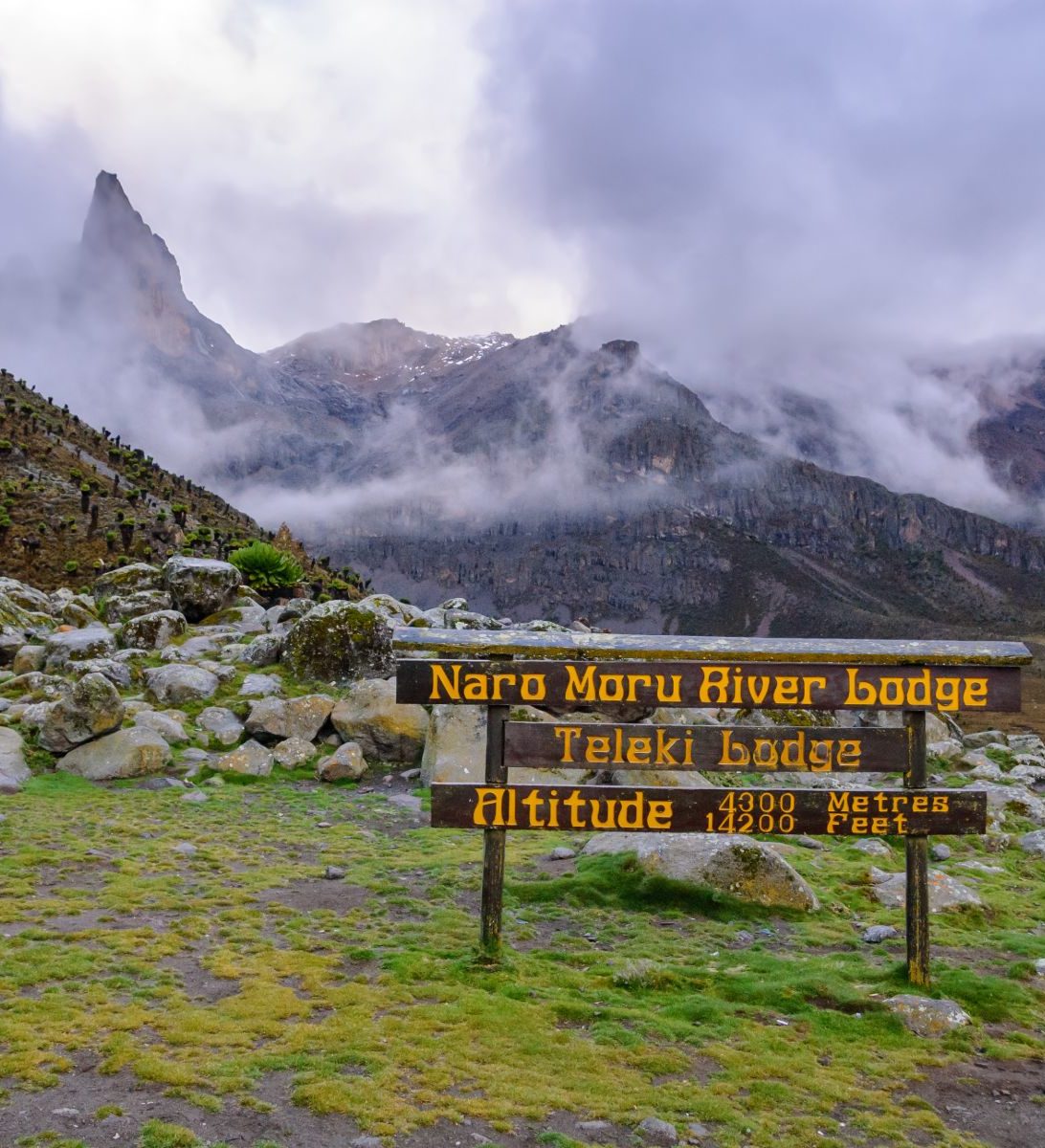 Rondreis-Kenia-Naro-Moru-Hiking-Trail-met-bordje-met-hoogte-aspect-ratio-382-420