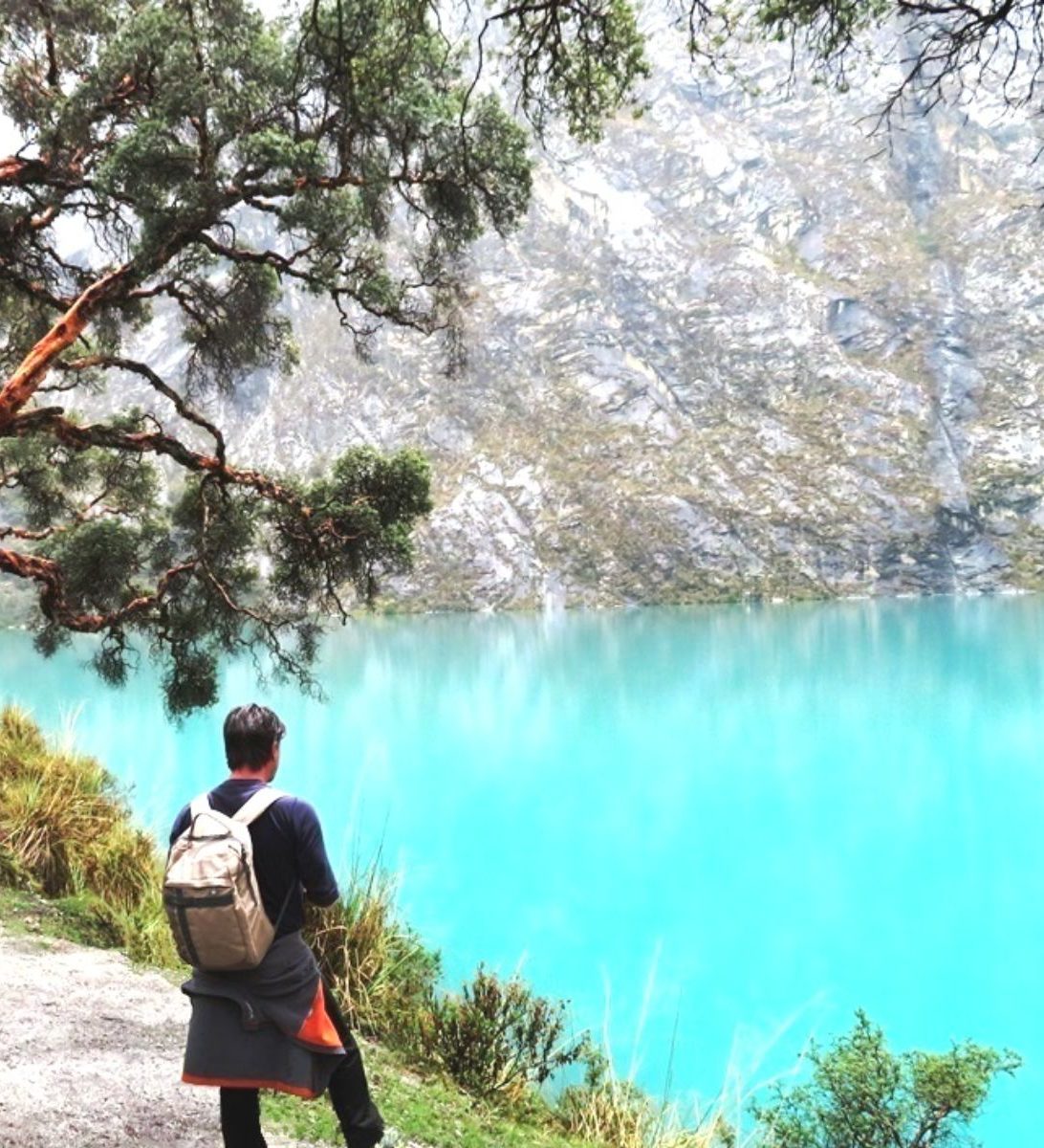 Rondreis Peru, Huaraz, meer met persoon en berg op achtergrond Rondreis Peru, Huaraz, meer met persoon en berg op achtergrond
